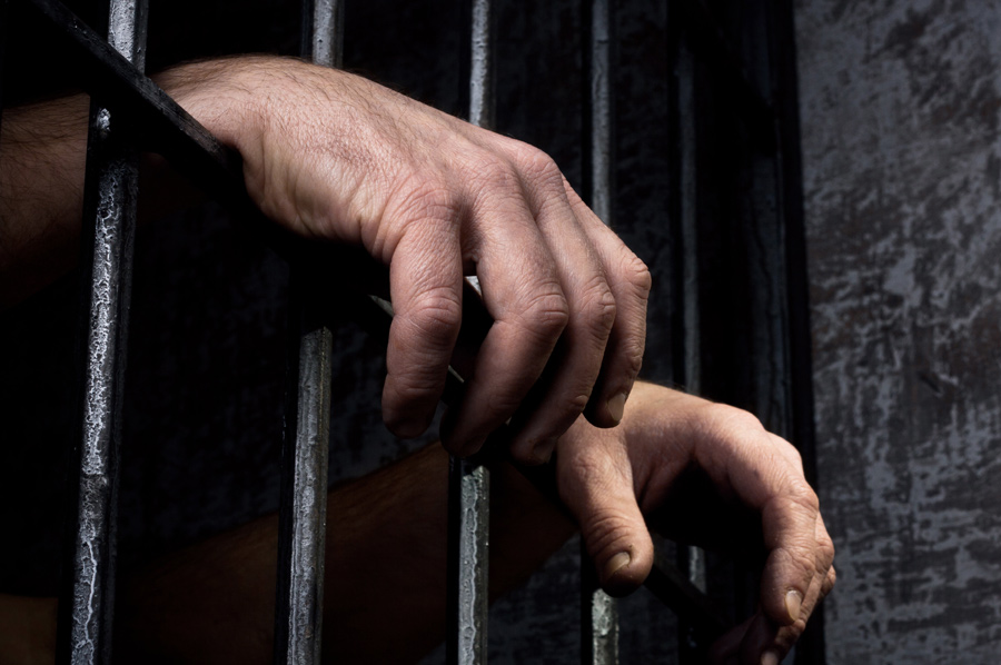 Hands gripping prison bars representing drug charge bail bond services